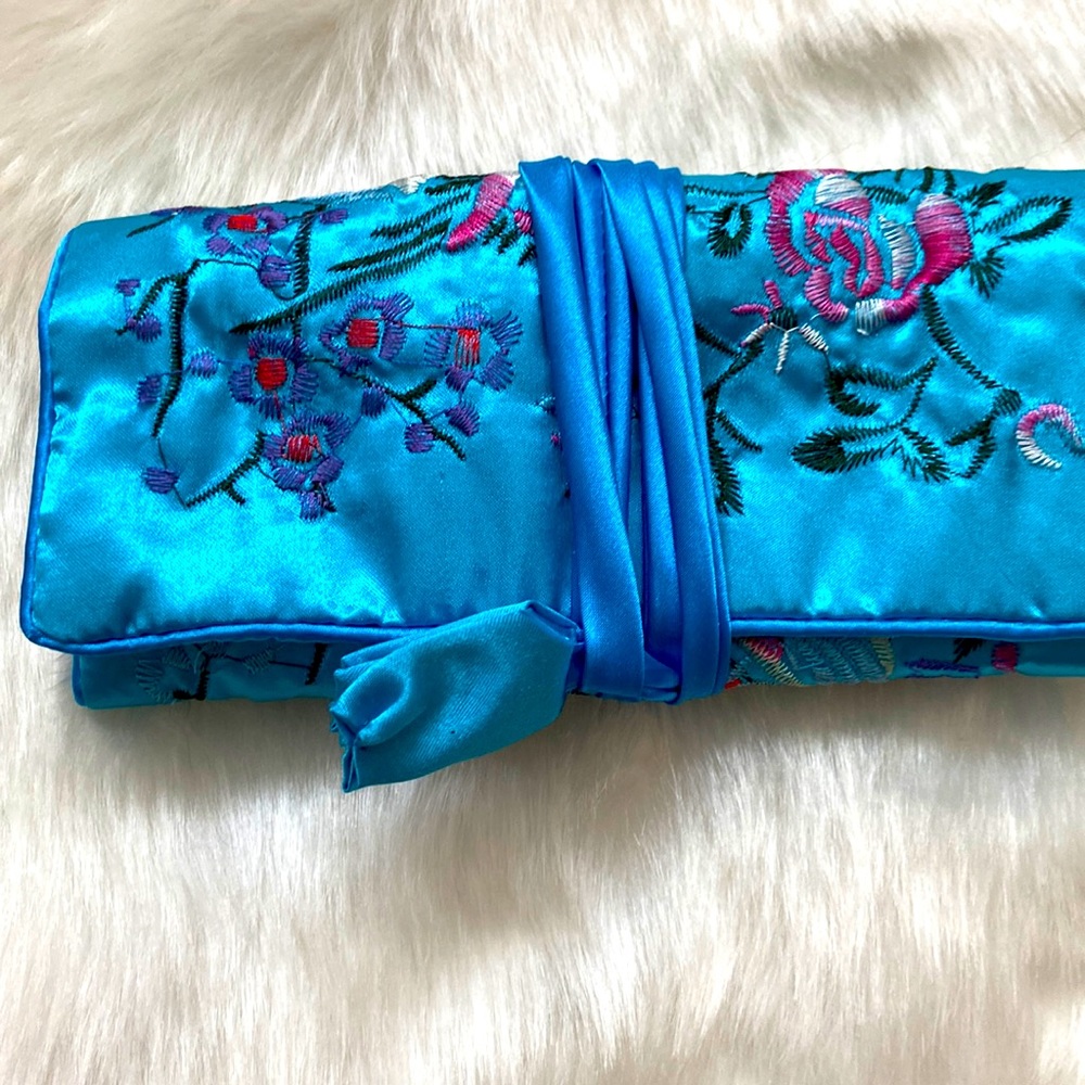 Blue embroidered jewelry roll.